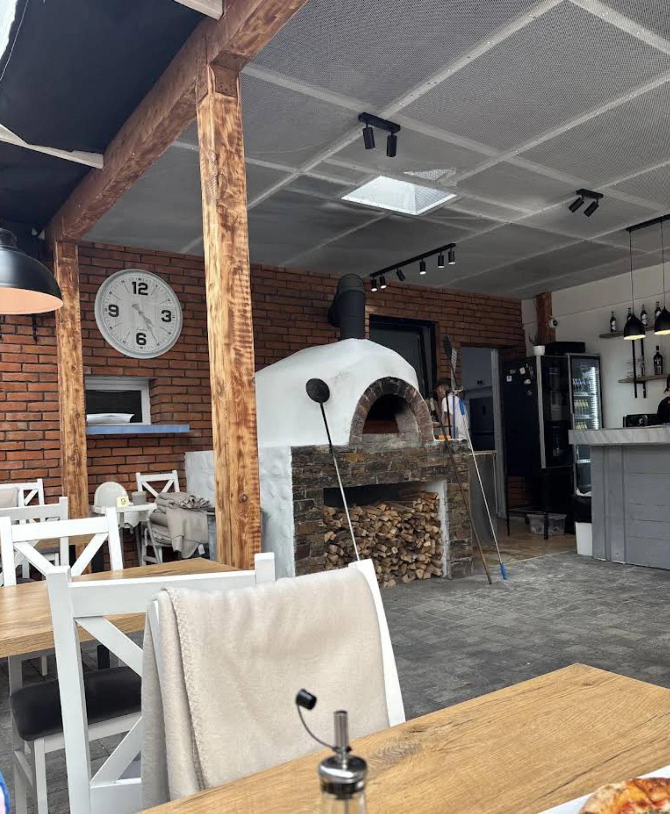 Piec opalany drewnem na środku lokalu Po prostu Pizza w Jantarze, ceglana ściana i drewniane stoły